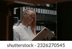 Small photo of Private detective analyzing gathered case clues in incident room, examining photos and doing background check. Police officer reading archive records and criminal evidence, studying clues.