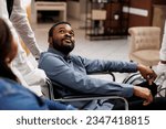 Happy young African American man using wheelchair during travel, receiving help and assistance in wheelchair-friendly and accessible hotel. People with mobility impairment and traveling