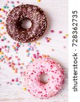 Small photo of Overtop view of donuts in and sweet candy on white wooden background. Delicious junk food