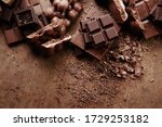 Small photo of Composition of bars and pieces of different milk and dark chocolate, grated cocoa on a brown background top view close up