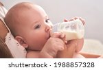 Small photo of Mom feeds her happy child son baby milk powder, baby bottle