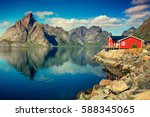 Beautiful fishing village on fjord. Beautiful nature with blue sky, reflection in water, rocky beach and fishing house (rorby). Lofoten, Reine, Norway