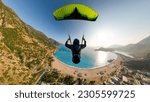 Small photo of Extreme paraglider pilot flying over the beach, adventure concept.