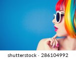beautiful woman wearing colorful wig and white sunglasses against blue background