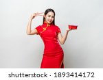 Pretty Asian woman in traditional red Chinese qipao dress holding plastic food box and chopsticks in studio isolated gray background