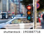 blurred view of city traffic with traffic lights, in the foreground a traffic light with a red light