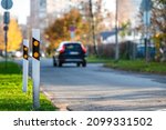 poles at the traffic safety speed bumps in residential area, blurred background with a car, closeup