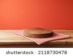 Small photo of Empty wooden podium with tablecloth for product display over red background. Holiday mock up for design and presentation