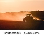 Silhouette of tractor working on a farm at twilight