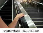 Small photo of Woman grabbing the escalator hand rail while standing on the escalator, woman going down the stair in the shopping mall by using escalator. Safety awareness in everyday life concept.