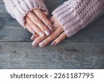 Small photo of Women is hands with a beautiful manicure on a wooden background. Autumn trend, polish the beige and quail egg pattern on the nails with gel polish, shellac. Copy space.