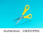 opened yellow scissors over turquoise blue background. conceptual photo of levitating scissors with central composition
