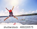 Kids jumping off a boat into the lake. Focus on boys legs and boat, lens flares from sun.