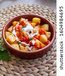 Small photo of Spanish cuisine potato snack with tomato and white sauce - patatas bravas, served in the red terracotta dish.