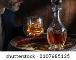 Small photo of Whisky tasting. Man sits in front of a barrel with a decanter and a glass of whiskey.
