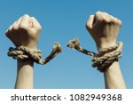 Hands tearing shackles the background of blue sky. Concept of freedom