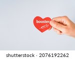 Small photo of senior hand holding red heart paper shape with booster word and syringe icon for vaccinated or inoculation booster dose due to spread of corona virus, population, social or herd immunity concept
