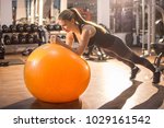 Fit girl workout with fitness ball in plank position in gym.