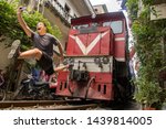Man with mobile phone makes dangerously selfie photo in front of moving train. An undisciplined tourist in the popular Hanoi railway street, Vietnam.