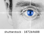Vision concept with a greyscale image of a mans eye with a crosshair focused on his iris which has been selectively colored blue.