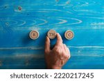 Conceptual image of trademark and copyrights - male hand placing three wooden cut circles with circled letter signs R, C and TM on them over textured blue wooden background.