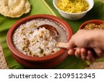 Small photo of Rice porridge, Kanji, gruel in clay pot palm mat background Kerala South India. congee, rice soup, green gram curry, chammanthi. Ayurveda diet for immunity. porridge Indian Sri lankan veg food.