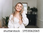 Small photo of Blonde smiling woman 35 year clean fresh face and hands with long hair in cozy knitted cardigan at the bright interior