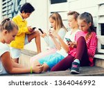 Cheerful children are chatting on their smartphone on walking.