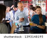 Small photo of Tipsy man trying to seduce young female colleague on office party at nightclub