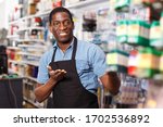 Small photo of Portrait of professional happy seller proffering goods in shop of household materials and tools