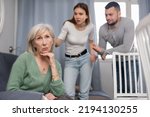Small photo of Chagrined senior woman having problems in relationship with young couple