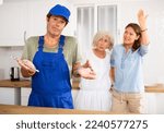 Small photo of Inept plumber throws up his hands. In the background, disgruntled apartment owners scold him