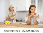 Small photo of Aggrieved woman having quarrel with her elderly mother in kithcen at home.