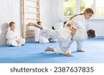 Small photo of Engrossed sportsmen boys and girls in pair conduct training battle in oriental fighting technique. School of martial arts. Reinforcement strength of mind and body. Sport to max