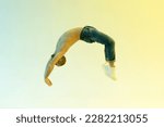 Small photo of Fit male athlete performing a flick flack jump or back handspring in a full length side view over a colorful studio background