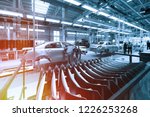 Worker looks into car body on production line. Factory for production of cars in blue. Modern automotive industry. Blue tone