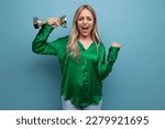 Small photo of adorable girl squeals with joy holding the championship cup on a blue bright background