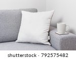 Blank white pillow on a couch with a tea cup.