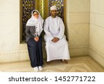 Small photo of Muscat, Oman - July 16, 2019: Arabian man and Slav woman in traditional clothes in Muscat Grand mosque. Sitting smiling middle aged couple. Miscegenation concept