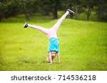 Small photo of Cute athletic schooler girl tumbling, turning, turn handsprings in the park. Sunny summer day. Sport for children. Kid doing gymnastic and having fun. Healty body.