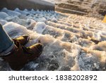 Danger of slipping. Female boots on rough slipper ice surface. A woman in brown leather shoes descends the slippery ice ladder.