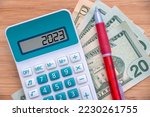 2023 numbers on a calculator and dollars banknotes, new year finance, money inflation and budget illustration