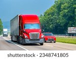 Small photo of Horizontal shot of a red eighteen wheeler leading traffic down an interstate highway.