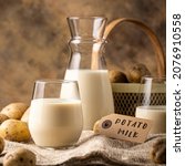 Small photo of Vegan plant based milk in transparent glasses and decanter. Alternative potato milk and potato tubers on sackcloth. Healthy vegetarian and vegan drink concept with copy space and text