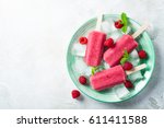 Homemade strawberry popsicles on green plate with ice, strawberries and mint. Healthy summer food concept with copy space.