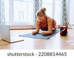 Small photo of middle-aged woman with curvaceous figure, overweight, blonde, stands in plank position, does yoga, sports, at home. Active lifestyle, keeping body in good shape for middle-aged women