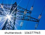 a high-voltage electricity pylons against blue sky and sun rays