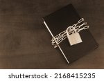Banned information and secure concept, book with chain and padlock on wooden table. Copy space for text