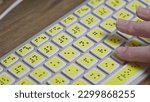 Small photo of Close-up of a computer keyboard with braille. A blind girl is typing words on the buttons with her hands. Technological device for visually impaired people. Tactilely touches bumps on the keys
