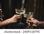 Small photo of A girl holds glasses of champagne in her hands, cheers with a man. Le coupe cocktail glasses. Celebrates the New Year or a corporate holiday. Disco or retro style. They bump glasses, clink glasses